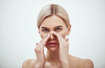 a concerned young woman touching her nose